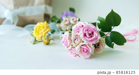 Bouquet of fresh roses, a package with flowers on a light background with a place for an inscription, the concept of a romantic congratulation, invitation, wedding, postcard, Valentines, shop Bouquet of fresh roses, a package with flowers on a light background with a place for an inscription, the concept of a romantic congratulation, invitation, wedding, postcard, Valentines, shop 85816125