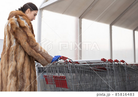The woman puts down the shopping cart and she is wearing latex gloves. Protection during a pandemic. The woman puts down the shopping cart and she is wearing latex gloves. Protection during a pandemic. 85816483