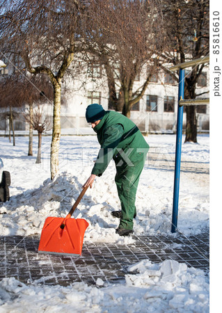 The landlord scrapes snow and ice with an orange cobblestone shovel 85816610