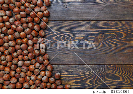 hazelnuts with shells laid on brown wooden table surface hazelnuts with shells laid on brown wooden table surface 85816862