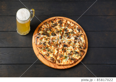 Top view of thin dough pizza with mushroom and a glass of lager beer on a table Top view of thin dough pizza with mushroom and a glass of lager beer on a table 85817022
