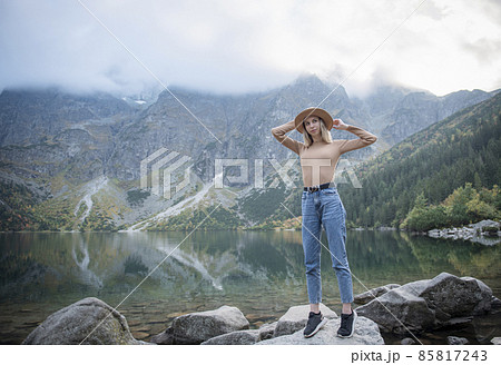 Young tourist woman in a hat with hands up on the top of the mountains 85817243