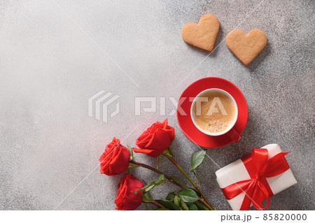Coffee and two heart shaped cookies for Valentine's day. Bouquet of red roses and love gift. Coffee and two heart shaped cookies for Valentine's day. Bouquet of red roses and love gift. 85820000