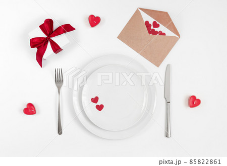 Valentines day or romantic dinner background. Festive romantic table setting with candles and a gift on a white background. Valentine's card. Valentines day or romantic dinner background. Festive romantic table setting with candles and a gift on a white background. Valentine's card. 85822861