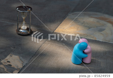 Blue and pink ceramic couple dolls hug with each other on stone background. Blue and pink ceramic couple dolls hug with each other on stone background. 85824959