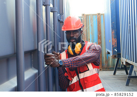 Close up of An African American handsome black engineer he is working in container box yard area of logistics transportation import export or shipping industry Close up of An African American handsome black engineer he is working in container box yard area of logistics transportation import export or shipping industry 85829152
