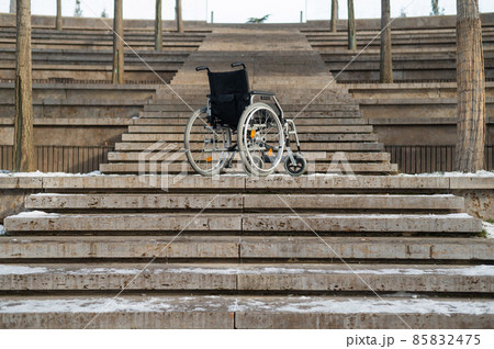 Wheelchair by the stairs without people outdoors.  85832475