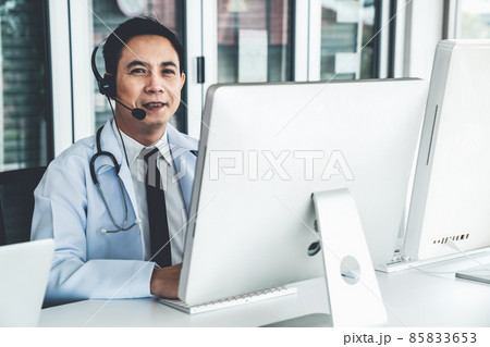 Doctor wearing headset talking actively on video call in a clinic or hospital . Doctor wearing headset talking actively on video call in a clinic or hospital . 85833653