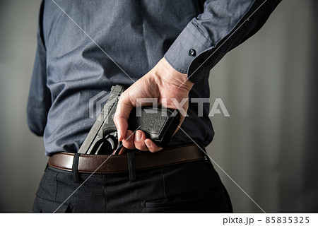 拳銃を構えるスーツの人物 85835325