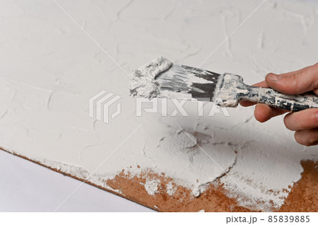 A spatula, the process of applying a layer of putty on a sheet of fiberboard. production of a textural background for subject shooting. A spatula, the process of applying a layer of putty on a sheet of fiberboard. production of a textural background for subject shooting. 85839885