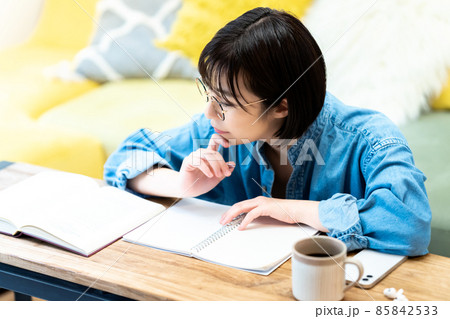 リビングで勉強する眼鏡の若い女性 リビングで勉強する眼鏡の若い女性 85842533