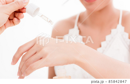Beautiful woman dropping serum collagen moisturizer into back of the hand Beautiful woman dropping serum collagen moisturizer into back of the hand 85842847
