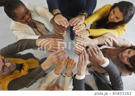 Happy diverse business team joining hands. Group of different mixed race multiethnic people standing in circle, reaching up their hands together and smiling. Overhead view from above. Teamwork concept Happy diverse business team joining hands. Group of different mixed race multiethnic people standing in circle, reaching up their hands together and smiling. Overhead view from above. Teamwork concept 85855262