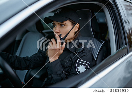 Policewoman using radio patrolling street in car 85855959