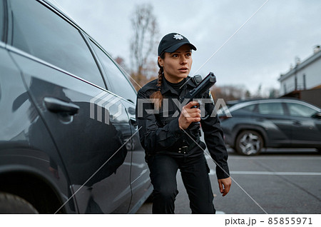 Police woman aiming gun standing near car 85855971