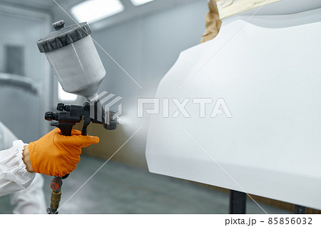 Technician in safety clothing spraying car paint Technician in safety clothing spraying car paint 85856032