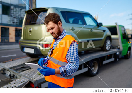 Male tow truck operator checking electronic invoice Male tow truck operator checking electronic invoice 85856130
