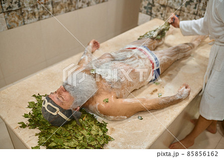 Elderly man getting massage with oak broom 85856162