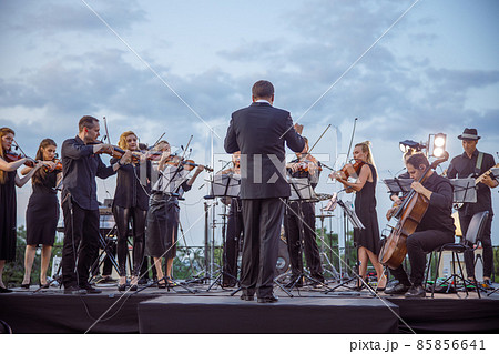 Orchestra playing classic instrumental music under cloudy sky 85856641