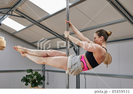 woman suspended in pole dance bar, with good age physique in the 40s 85859531
