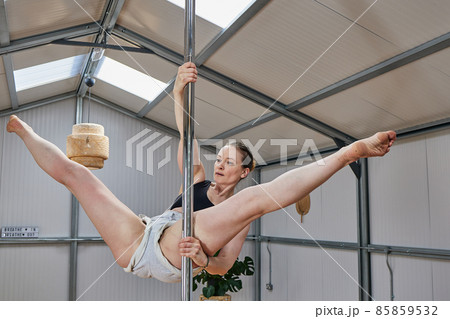 woman suspended in pole dance bar, with good age physique in the 40s woman suspended in pole dance bar, with good age physique in the 40s 85859532