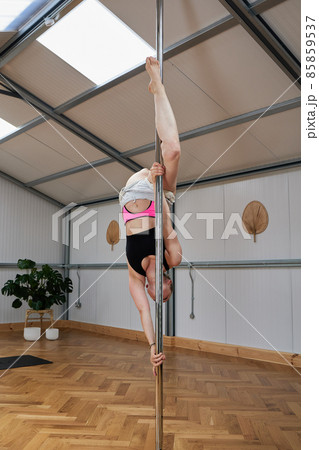 pole dancer in vertical format in a clear studio doing exercises 85859537