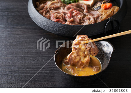 すき焼き肉を生卵に漬けて食す 85861308
