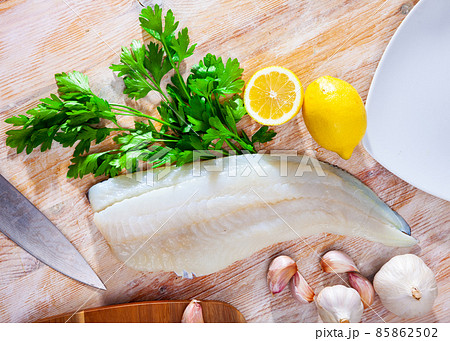 Raw codfish fillet on wooden table with condiments 85862502