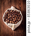 Burlap bag with coffee beans on wooden background 85863010