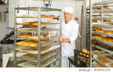 male baker rolling cart with bread in kitchen male baker rolling cart with bread in kitchen 85863149