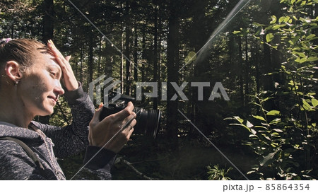 Traveler photographing scenic view in forest. One caucasian woman shooting nice magic look. Girl take photo video on dslr mirrorless camera. 85864354