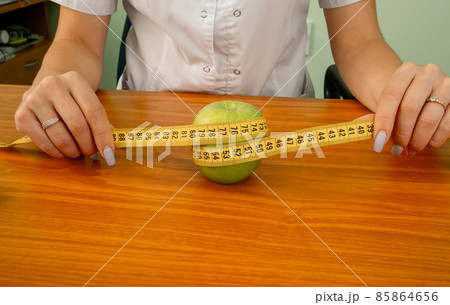 Green apple measured the meter in a female hand. 85864656