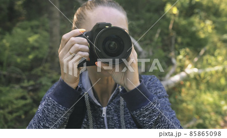 Traveler photographing scenic view in forest. One caucasian woman shooting close up look. Girl take photo video on dslr mirrorless camera. 85865098