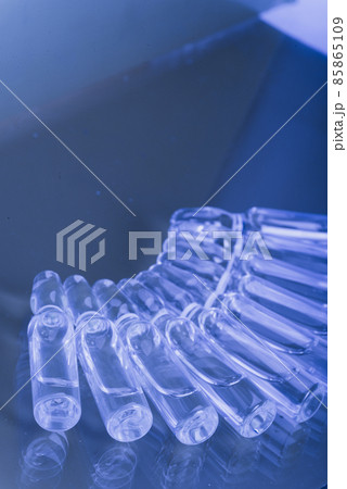 Glass medical ampoule vial for injection. Medicine is liquid sodium chloride with of aqueous solution in ampulla. Close up. Bottles ampule multicolor. 85865109