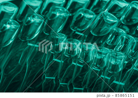 Glass medical ampoule vial for injection. Medicine is liquid sodium chloride with of aqueous solution in ampulla. Close up. Bottles ampule multicolor. 85865151