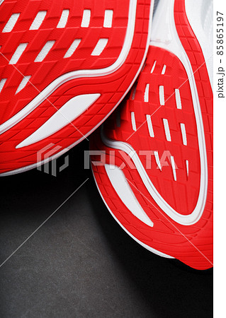 Running shoes with red soles on a black background. 85865197