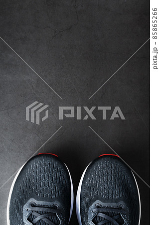 Black sports sneakers with red soles on a black background. 85865266