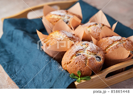 A group of muffins with berries and chocolate on a tray. Front view. 85865448