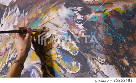 Artist designer draws an eagle on the wall. Craftsman decorator paints a picture with acrylic oil color brush. Close-up dark magic cinematic look. 85865493