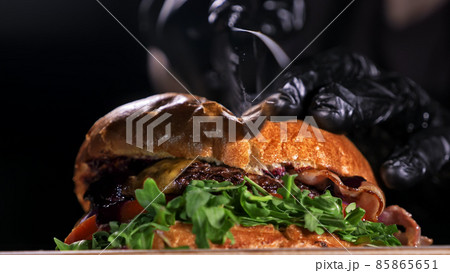 Cut craft burger is cooking on black background. Consist: sauce, lettuce, tomato, red onion, pickle, cheese, bacon, air bun and marbled meat beef. Cut craft burger is cooking on black background. Consist: sauce, lettuce, tomato, red onion, pickle, cheese, bacon, air bun and marbled meat beef. 85865651