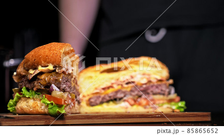 Cut craft burger is cooking on black background. Consist: sauce, lettuce, tomato, red onion, pickle, cheese, bacon, air bun and marbled meat beef. Cut craft burger is cooking on black background. Consist: sauce, lettuce, tomato, red onion, pickle, cheese, bacon, air bun and marbled meat beef. 85865652