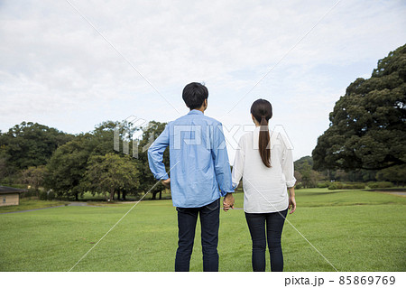 若い日本人カップルの後ろ姿、夏の朝、公園の芝生 85869769