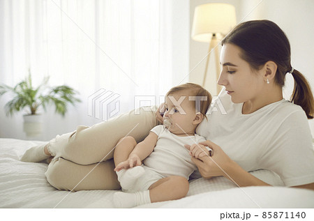 Loving young Caucasian mother relax on bed at home cuddle with baby infant. Caring happy mom rest lie in bedroom with cute little newborn kid child together. Motherhood concept. Fertility and ivf. Loving young Caucasian mother relax on bed at home cuddle with baby infant. Caring happy mom rest lie in bedroom with cute little newborn kid child together. Motherhood concept. Fertility and ivf. 85871140