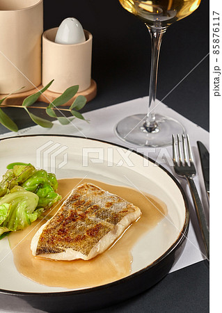 Delicious fish cooked in an oven and garnished with sauce and cabbage. Delicious fish cooked in an oven and garnished with sauce and cabbage. 85876117