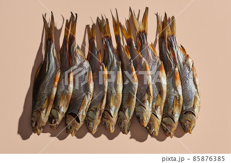 Lots of dried or jerky salty roach, palatable clipfish on pink background. Famous beer snack. Traditional way of preserving fish. Close up Lots of dried or jerky salty roach, palatable clipfish on pink background. Famous beer snack. Traditional way of preserving fish. Close up 85876385