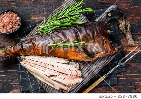 Cut Hot smoked fish on a wooden board with rosemary. Dark wooden background. Top view 85877980
