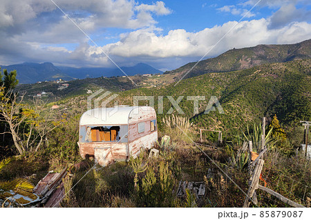 Old abandoned rusted roulotte Rv van in green field 85879087