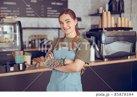Cheerful female barista in apron standing in coffeehouse 85879394
