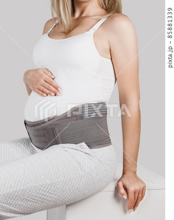 Pregnant woman belly in prenatal pregnancy maternity belt. Orthopedic abdominal support waist, back, abdomen band. Belly brace or band for pregnancy. Horizontal web banner. Torso of pregnant model. 85881339