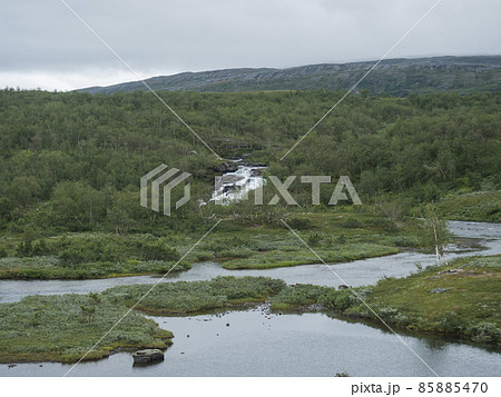 Lapland landscape with river, small waterfall, green mountains, birch trees forest. Sweden summer moody and foggy wild nature, Padjelantaleden hiking trail. Lapland landscape with river, small waterfall, green mountains, birch trees forest. Sweden summer moody and foggy wild nature, Padjelantaleden hiking trail. 85885470